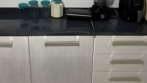 Une cuisine dotée d’un plan de travail noir, de meubles blancs et de divers appareils de cuisine, notamment une machine à café et un mixeur.