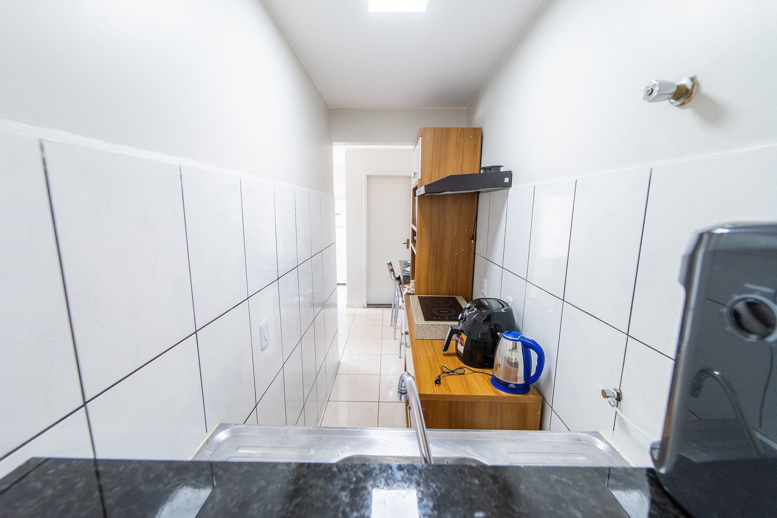A narrow kitchen with white tiled walls, a wooden countertop, and a built-in oven.