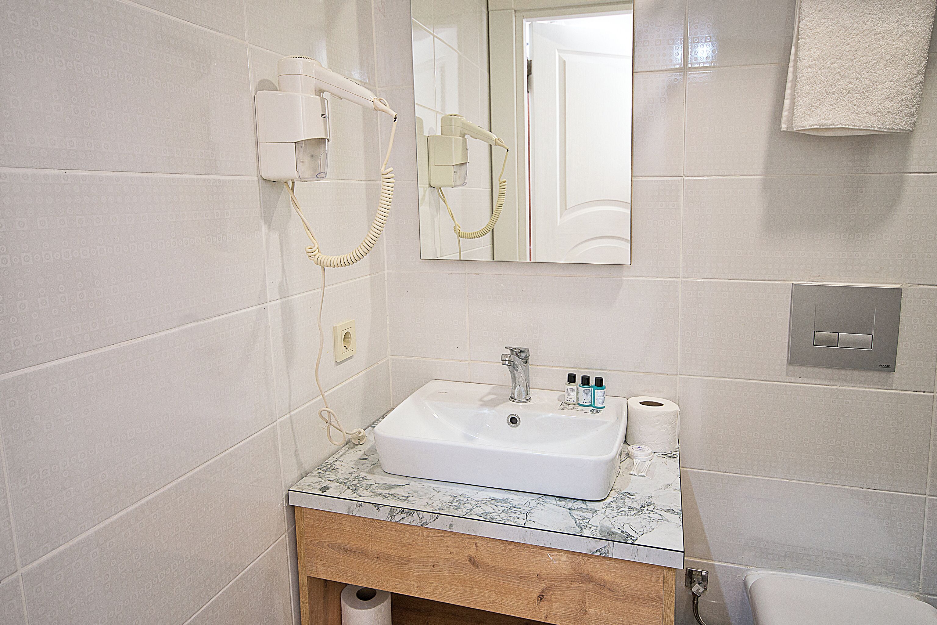 A bathroom with a white sink, mirror, and towel hanging on the wall.