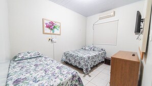 A room with two beds, a wooden cabinet, a wall-mounted TV, and a painting of flowers. - Kitnet 20% off, Full Kitchen, up to 4 Guests, Jr Catito (Brasília)