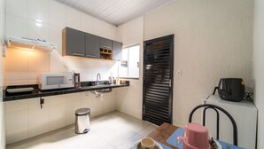 A compact kitchen with white cabinets, a microwave, a coffee maker, and a sink. - Kitnet 20% off, Full Kitchen, up to 4 Guests, Jr Catito (Brasília)
