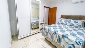 Een slaapkamer met een bed, een kledingkast en een spiegel.