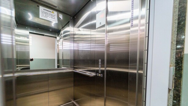 Een lege lift met roestvrijstalen wanden en een bordje dat roken verbiedt.