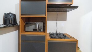 A compact kitchen with a microwave, toaster, and gas stove. - Ap 73m2, 2 bedrooms with suite, Up to 6 Guests, 1G Wi-Fi, Jr Catito (Brasília)