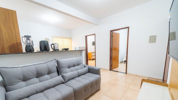 A modern living room with a grey sofa, a coffee maker, and a blender on a shelf. - Ap 75m2, 2 Bedrooms/suite, Up to 7 Guests, WI-FI 1G, Jr Catito (Brasília)