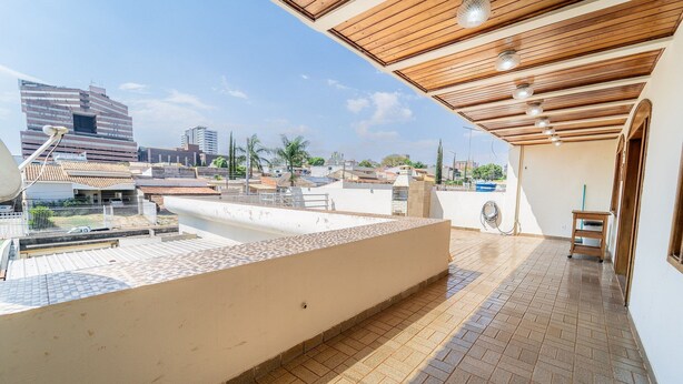A rooftop terrace with a tiled floor, a wooden ceiling, and a view of the cityscape.
