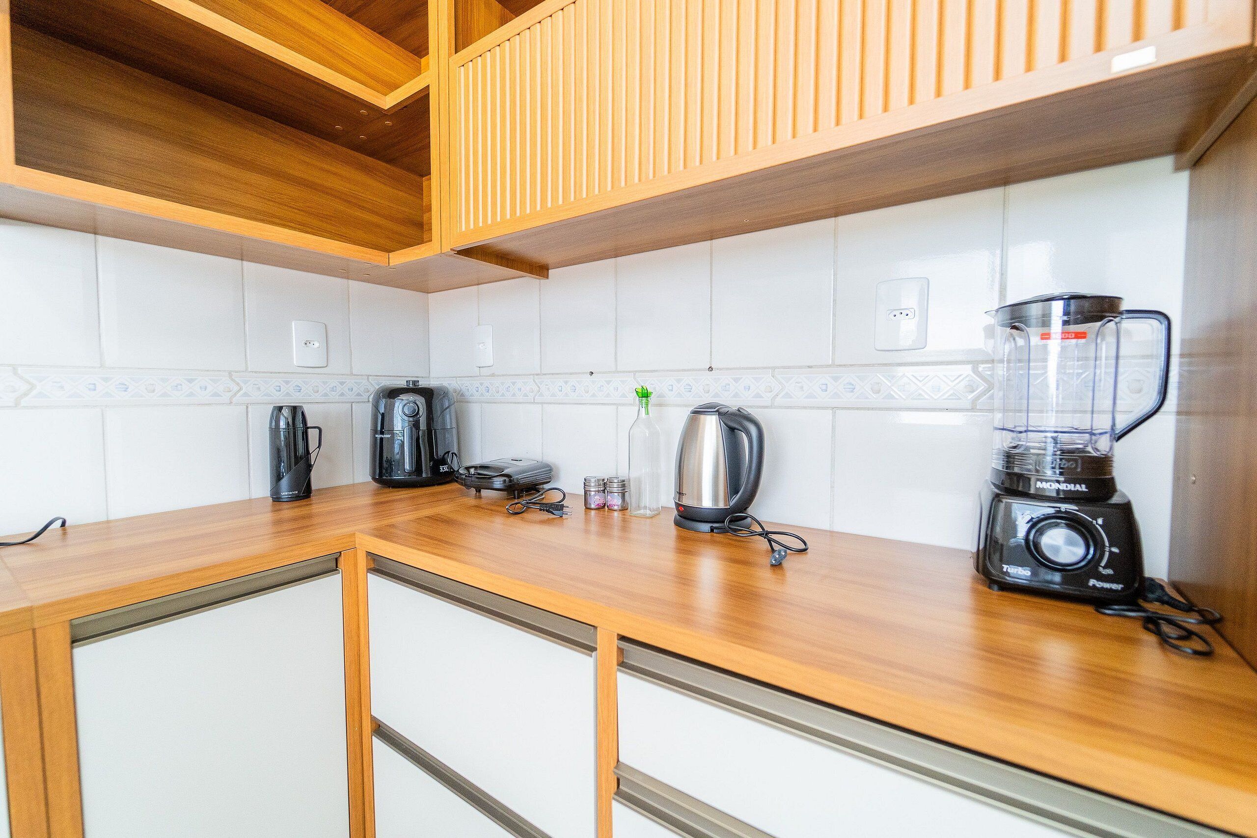 Una cocina con armarios de madera, una encimera, una licuadora, un hervidor y una cafetera.
