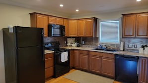 Una cocina moderna con armarios de madera, un refrigerador negro, una estufa y un lavavajillas.