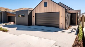 A modern single-story house with a large garage, a small attached shed, and a landscaped driveway. - Cosy ski retreat on The Remarkables Ski Area. 5 minutes to Jacks Point Golf Club (Jacks Point)