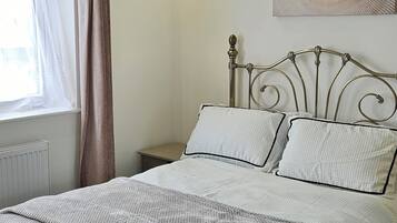 Una camera da letto con un letto, un comodino, una lampada a parete, una finestra con tende e una luce a soffitto.