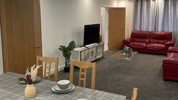 Un salon moderne avec un coin repas, un canapé en cuir rouge et un téléviseur.