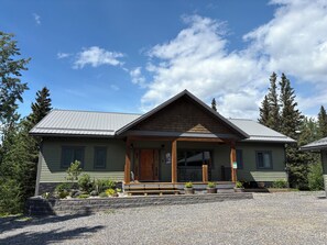 A two-story lodge with a wooden front porch and a stone foundation. - Alpine Adventure at Jasper East Gates (Folding Mountain Village)
