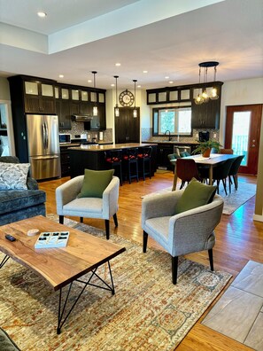 A spacious living area with a large island, dark wooden cabinets, and a modern kitchen in the background. - Alpine Adventure at Jasper East Gates (Folding Mountain Village)