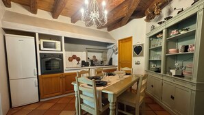Una cocina con armarios de madera, una mesa de comedor y una araña.
