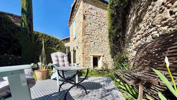 Un patio con alfombra estampada, una silla acolchada y una mesa.