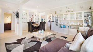 A spacious living room with a dining area, a large white cabinet with glass doors, and a modern coffee table. - Beautiful, Luxury, Water Front with Pool House (close to all amenities)  (Bundall)