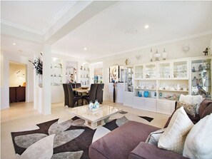 Relax and socialize in this stylish living room with a plush sofa, dining area, and beautiful artwork.