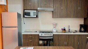 A compact kitchen with wooden cabinets, a built-in microwave, a stove, and a coffee maker.