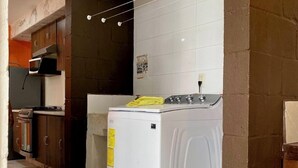 A compact kitchen with a washing machine, a microwave, and a stove.