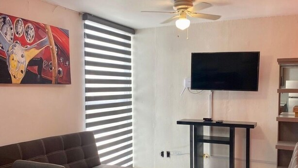 A living room with a sofa, ottoman, and a TV on a stand.