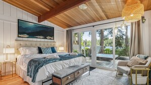 Ein Schlafzimmer mit einem großen Bett, einer Bank, einem Stuhl und Blick ins Freie.