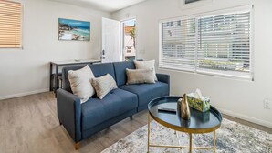 A living room with a blue sofa, a small round table, and a painting on the wall.
