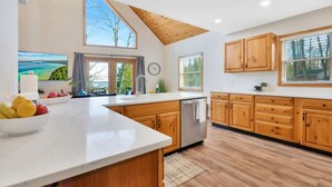 A kitchen with wooden cabinets, a white countertop, and a large window. - Lake View Fully Stocked Family Retreat - Paddleboards, Firepit, Games, EV outlet (Roscommon)