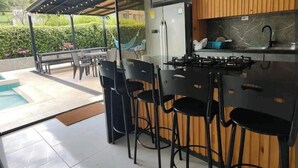 Een moderne keuken met een gasfornuis, houten keukenkastjes en uitzicht op een zwembad.