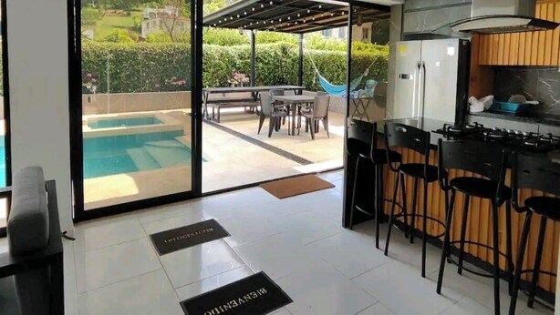 Een moderne keuken met een bar, een zwembad en een terras met buitenmeubilair.