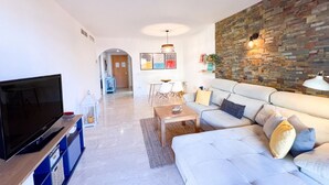 A modern living room with a flat-screen TV, a sofa, a coffee table, and a stone accent wall.