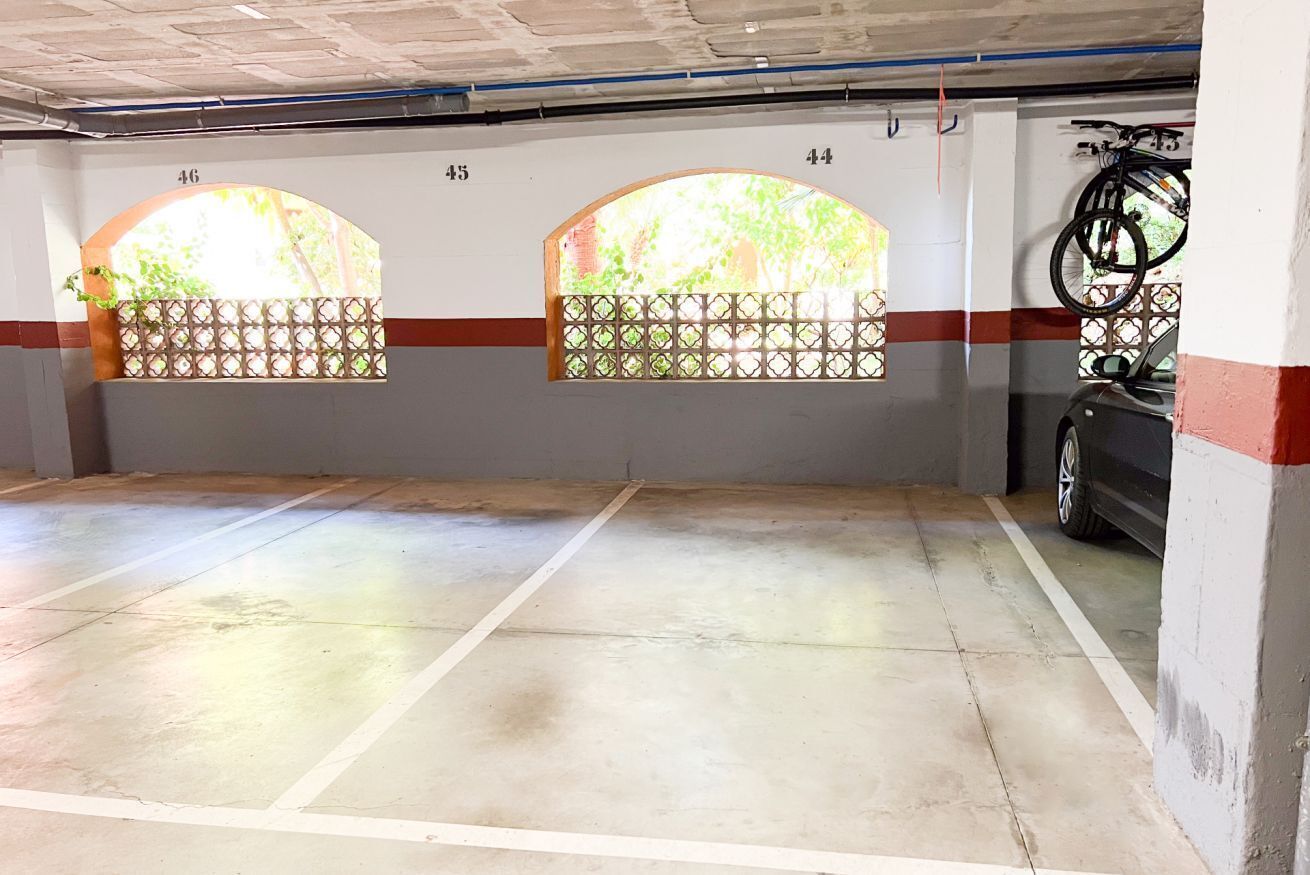 A parking garage with numbered parking spaces, a bicycle rack, and a car parked in one of the spaces.