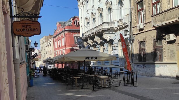 A street with outdoor seating, a Pepsi umbrella, and a building with ornate architecture.