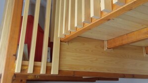 A wooden staircase with a handrail and a clock on the wall below.