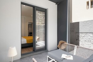 A modern room with a sliding glass door leading to a balcony, a bed with a yellow bedspread, and a seating area with a table and chairs. - Holidays in Funchal - Golden City A (Funchal)