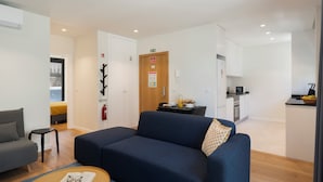 A modern living room with a sofa, a small table, and a kitchenette in the background. - Holidays in Funchal - Golden City B (Funchal)