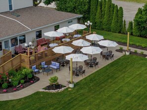 A patio area with outdoor seating and umbrellas, surrounded by a wooden deck and a lawn. - Stay in Style! Family Getaway by the Erie Shores (Marblehead)