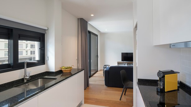 A modern kitchen with a black countertop, a built-in sink, and a coffee machine. - Holidays in Funchal - Golden City C (Funchal)