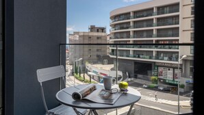 A balcony with a table, chair, and a view of a cityscape with buildings and a street. - Holidays in Funchal - Golden City D (Funchal)