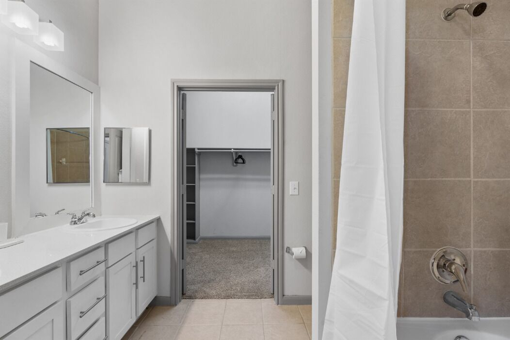 A modern bathroom with a white sink, mirror, and shower.