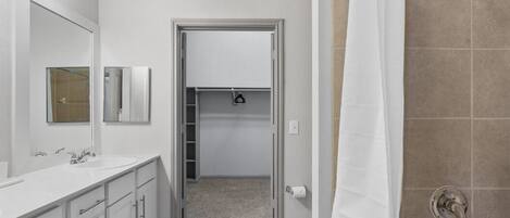 A modern bathroom with a white sink, mirror, and shower.