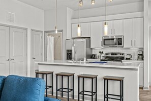 A modern kitchen with white cabinets, a central island, bar stools, and pendant lighting. - LUX 2B2B w/Pool & Parking near the Heart of Austin (Austin)