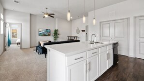A modern kitchen with white cabinetry, a large island, and pendant lighting. - LUX 2B2B Apt Near Heart of Austin w/Pool & Parking (Austin)