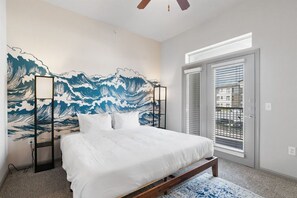 Een slaapkamer met een bed, een wanddecoratie met een groot golfpatroon, een raam met zonwering en een plafondventilator.