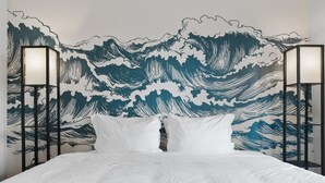 A bed with white bedding, a headboard with a wave pattern mural, and two wall-mounted lamps. - LUX 2B2B Apt Near Heart of Austin w/Pool & Parking (Austin)