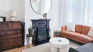 Un salon avec une cheminée, un canapé, une table basse et un grand miroir.