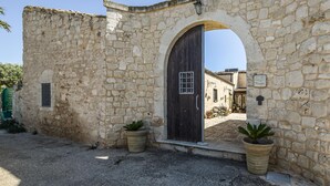 A stone building with a large arched doorway, potted plants, and a sign reading "La Nuragia". - Gorgeous home in Santa Croce Camerina (Santa Croce Camerina)