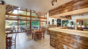 A restaurant with wooden interior, large windows, and a bar area.
