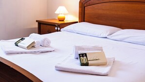 Een net opgemaakt bed met witte lakens en twee sets toiletartikelen aan de zijkant.