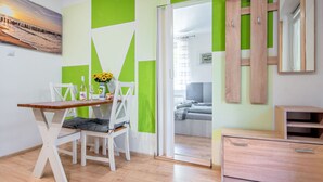 A modern room with a wooden dining table, white chairs, a green and white wall design, a wooden wardrobe, and a bed with a gray headboard. - 2 osobowy by Interhome (Warnowo)