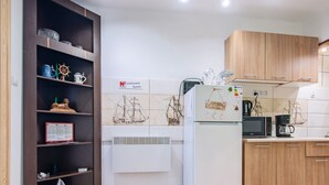 A modern kitchen with a white refrigerator, wooden cabinets, and a tiled backsplash featuring ship designs. - 2 osobowy by Interhome (Warnowo)